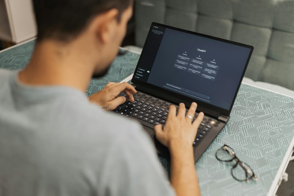 pexels photo 16094041 16094041 Man using laptop with AI interface, typing with focused attention. Indoors with eyewear beside.