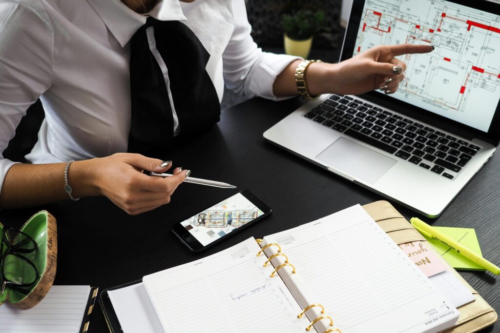 pexels photo 313691 313691 A business professional working on real estate project plans using multiple devices in an office setting.