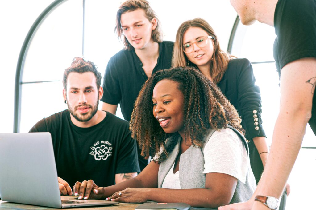 pexels photo 3153198 3153198 A diverse group of young professionals collaborating around a laptop in a modern office setting. Perfect for business or tech concepts.