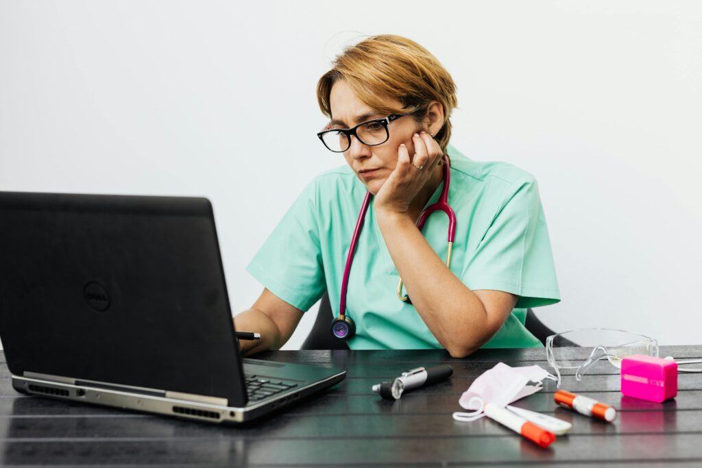 pexels photo 5207113 5207113 Focused nurse with eyeglasses working on a laptop surrounded by medical tools on a desk.