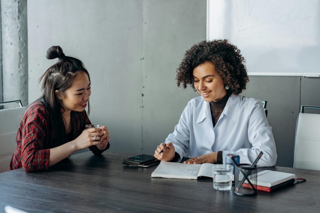 pexels photo 8297623 8297623 Two women in a modern office setting engaging in a collaborative discussion.